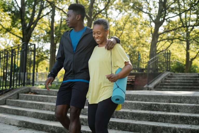 A joyful mother and son walking down park stairs, enjoying a sunny outdoor day.